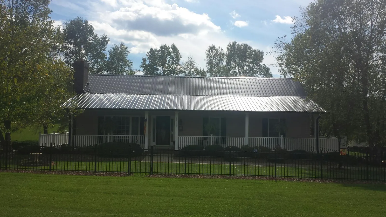 Gray metal roof on a brick ranch with a full width front porch — Gutter Guard Installation work by our crew in Dix