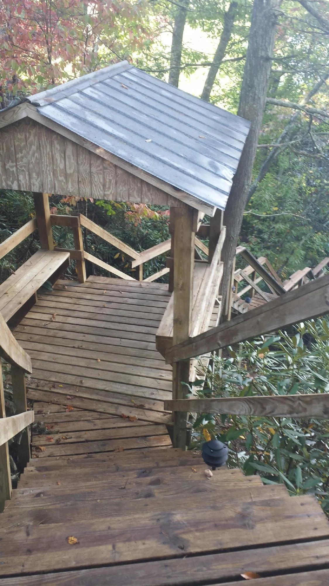 Metal roofed shelter over wooden steps on a wooded walkway — Skylight Repair & Installation work by our crew in Dix